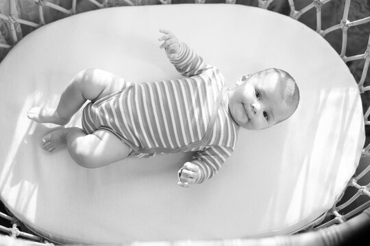 Black and white photo. Adorable newborn baby is resting in bed. Family morning at home.