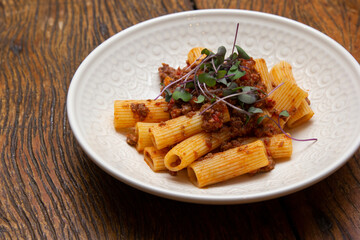 Rigatoni pasta with sugo sauce and lamb ragout, with coriander leaves on top.