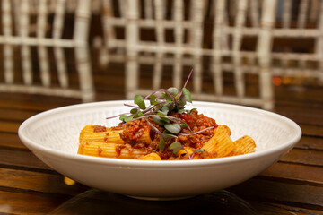 Rigatoni pasta with sugo sauce and lamb ragout, with coriander leaves on top.