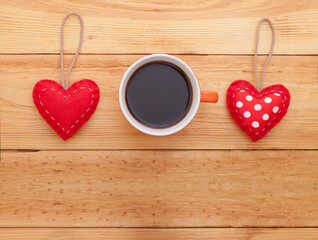 Red hearts and cup of coffee on wooden table