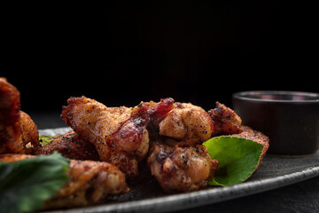 BBQ chicken legs with sauce, on a gray plate, on a dark background