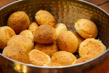 Brazilian cheese bread in a pan on wooden table.