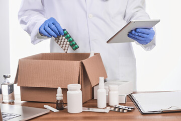 Doctor looking at a diagnosis on a tablet and packing drugs for a patient