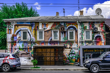 Fototapeta na wymiar Kharkiv, Ukraine - July 20, 2020: Old house with a beautiful modern mural on the wall in Kharkov (Kotsarska street 36/38). Colorful painting on the facade of a small two-story building