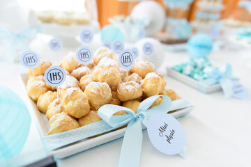Sweet puffs sprinkled with powdered sugar on a candy bar at the first communion party