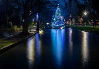 Illuminated Christmas tree in the river at Bourton-on-the-Water in the Cotswolds.