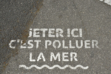 "Jeter ici c'est polluer la mer" écrit sur la chaussée à Narbonne, Aude, Languedoc, Occitanie.