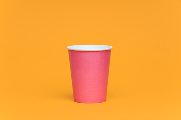 Pink paper cup on an orange background, take away coffee concept. 