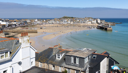 Fototapeta na wymiar View over St Ives town and and its harbour’s breakwater on a sunny summer’s day with tide out