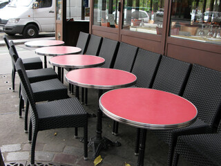 Empty street cafe with black chairs and red round tables in a rainy autumn day in Paris