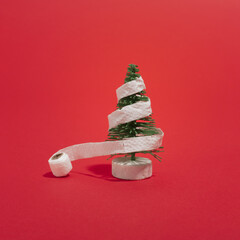 Shitty Christmas/ Covi-tree / A tiny fir tree decorated with a toilet paper roll. Background is red.