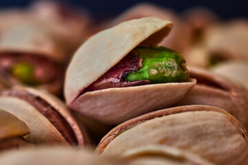 Close-up of green pistachio with open shell, next to more pistachios