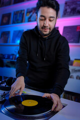 Dj colocando un disco de vinilo en su tocadiscos mientras mezcla música en una tienda de discos....