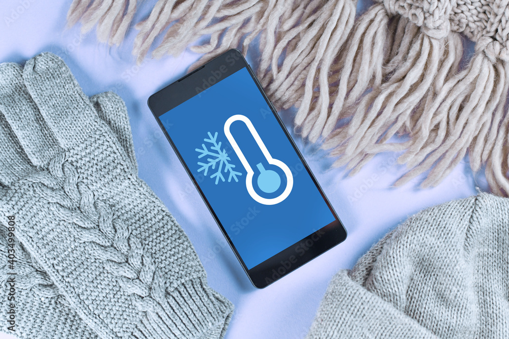 Wall mural concept for cold temperatures with snow and minus degrees with mobile phone showing weather forecast