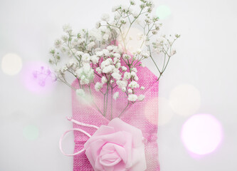 White spring flowers in a decorative pink fabric envelope. The concept of love, birthday, valentine's day.