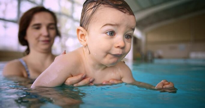 Mother teaching baby son to swim in indoor pool