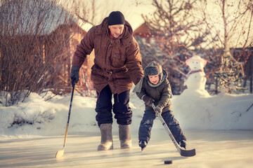 Father is teaching his little son to play hockey in Russia. Image with selective focus, toning and...