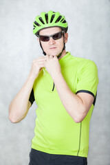 Portrait of an athlete cyclist on a light background in a helmet and a light green t-shirt.