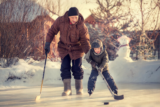 Father is teaching his little son to play hockey in Russia. Image with selective focus, toning and noise effect.