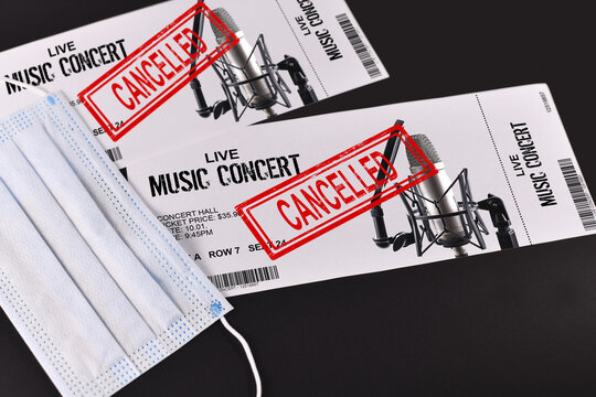 Concept for cancelled entertainment events during Corona virus pandemic with concert tickets and red 'cancelled' stamp on them and face mask