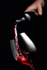 Naklejka na ściany i meble Pouring red wine in a glass goblet.