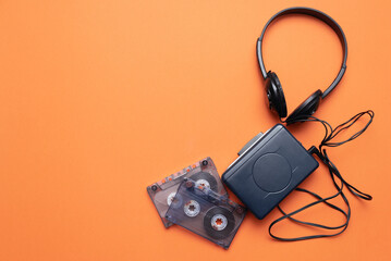 Old retro stereo cassette player and headphones on the orange flat lay background.