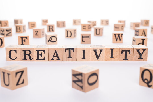 Creativity concept. Close up view photo of wooden cubes making showing word creativity on white table background