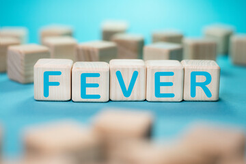 Word FEVER on wooden blocks on blue background
