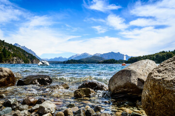 Fototapeta na wymiar Rocks from the shore of a lake in summer. Pines, mountains, crystal clear water.