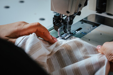 Closeup shot of seamstress hands working on sewing machine