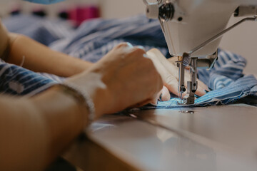 Selective focus shot of seamstress hands working on sewing machine
