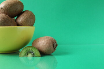 still life kiwi fruit in a yellow bowl plate and next to a kiwi copyspace slice
