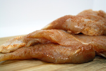 Chicken fillet pieces on a wooden board.