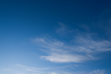 Fototapeta na wymiar Blue deep sky with a few clouds illuminated by the setting sun.