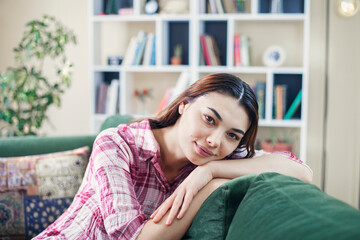 Obraz premium Happy young woman lying on couch and relaxing at home, casual style indoor shoot