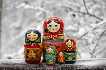 Set of Matryoshka Russian dolls in traditional bright colored clothes standing in the winter background