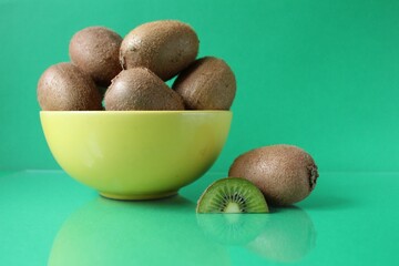 still life kiwi fruit in a yellow bowl plate and next to a kiwi copyspace slice