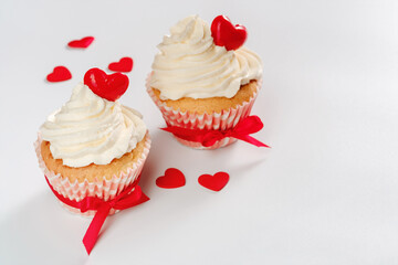 Two valentines cupcakes with hearts shaped caramel candy tied red ribbons on white background. High quality photo, copy space for text