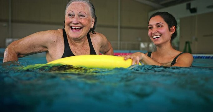 Happy senior woman and swimming coach in pool aerobics class