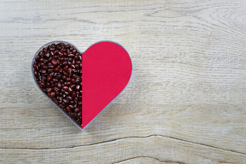 Obraz premium Fresh red bean in a heart shaped mold rests on a wooden table and has a copy space.