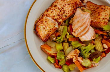 Baked salmon garnished with asian vegetables. Top view.