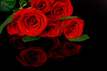 Bouquet of beautiful red roses isolated on black background with reflection.