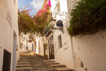 Beautiful narrow street with cobblestone stairs in an old town with white houses and tiled roofs. Altea, Spain