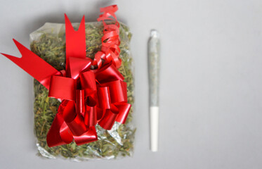 A long big joint of marijuana with a bag of cannabis and a gift bow and space for your text