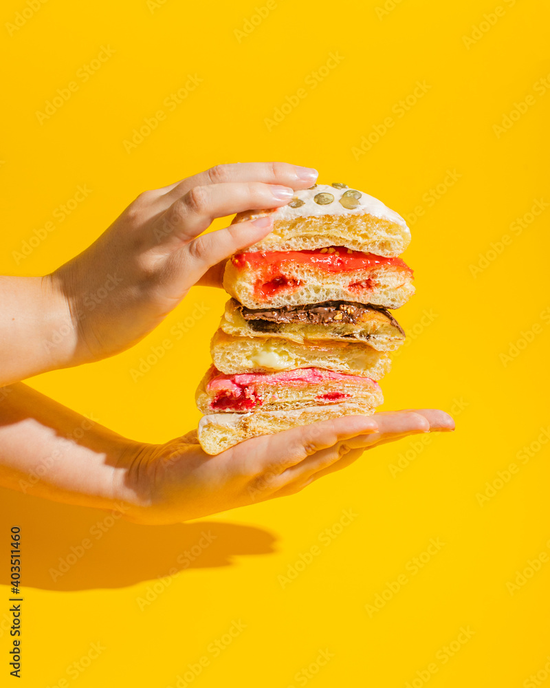 Poster stack of different donuts with toppings in hands on yellow background
