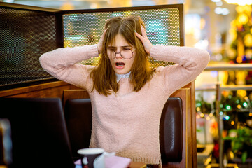 Tired business woman working on her workspace.Angry girl student in cafe with laptop