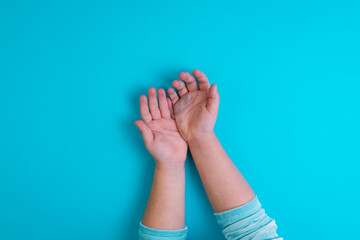 Hands of little girl on blue background. Conceptual. Top view. Copy space