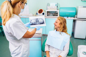 Dentist and the patient examine image of the dental cavity, teeth, in order to choose a treatment in consultation with medical equipment. Correction of bite deficiencies. Deep tooth canal treatment