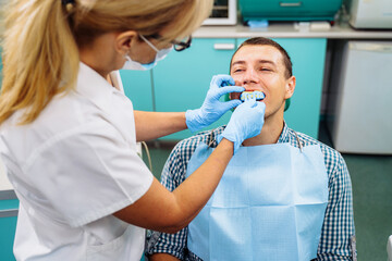 Making cast of the upper row of teeth using a special plate and soft material. Preparation for installing crowns. Dental procedures in a modern clinic. Orthodontic silicone trainer