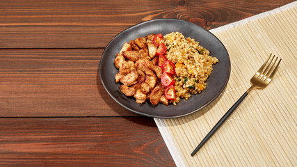 Fried chicken fillet in slices and bulgur on a plate on a wooden background cherry tomatoes on a wooden background with a place to copy